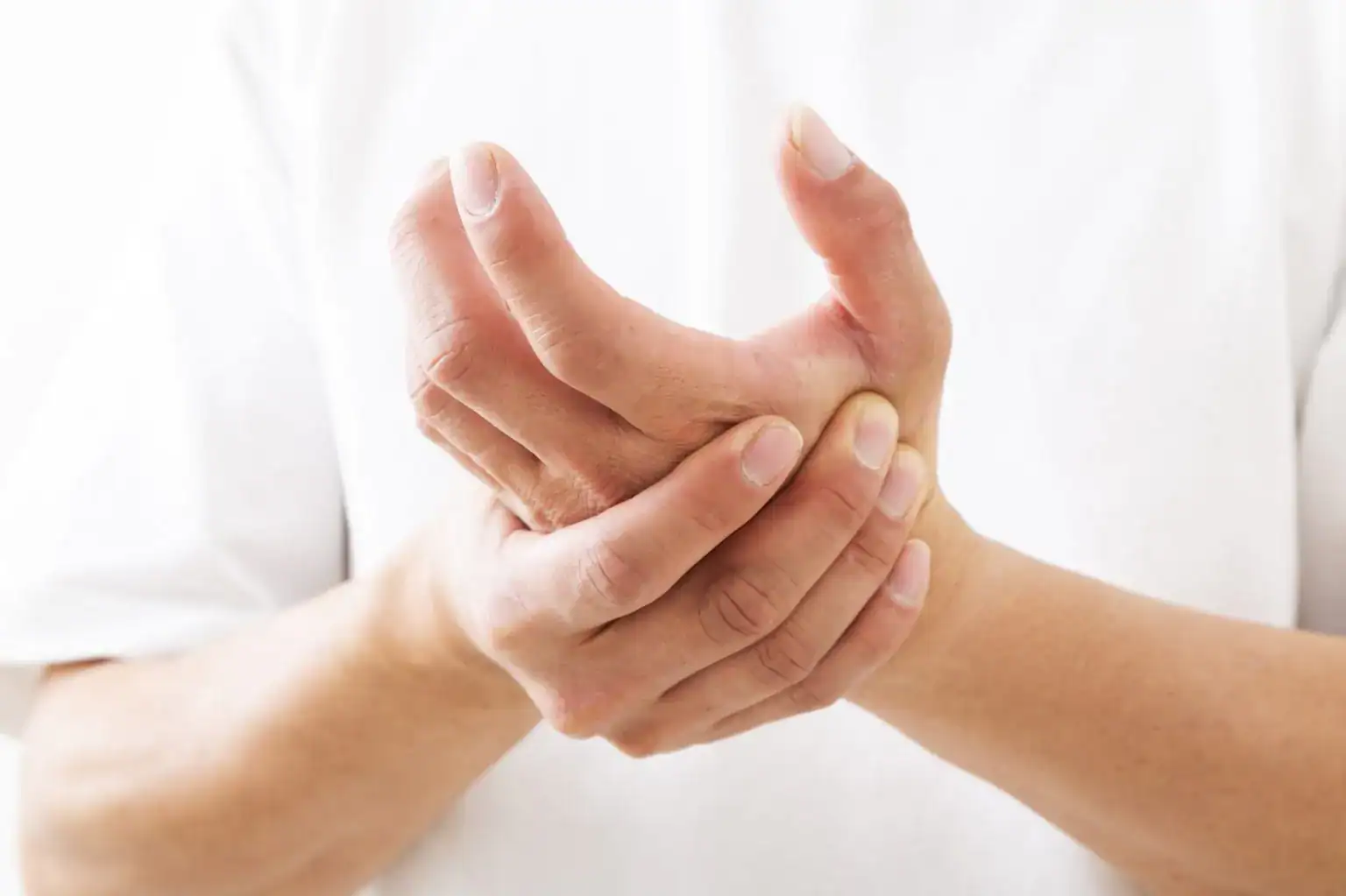 手のしびれに悩み、反対の手で手首をかばうように押さえている人物のイメージ
