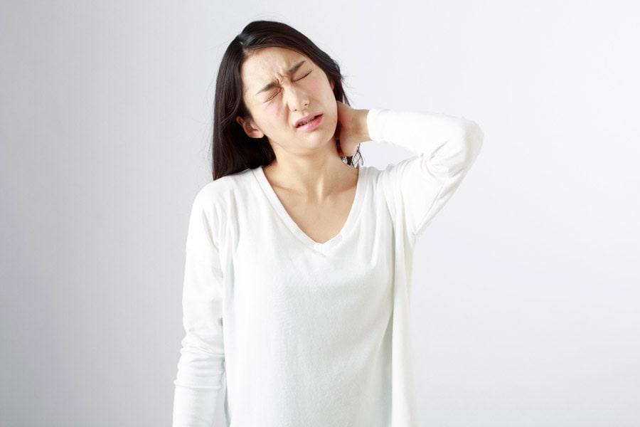 頚椎症で首を痛そうに押さえている女性のイメージ画像