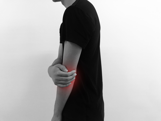 テニス肘で痛む肘を押さえているイメージ画像