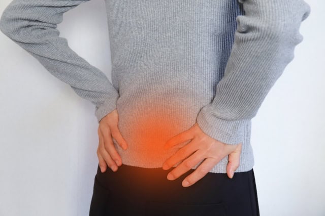 脊柱管狭窄症で痛い腰を押さえている女性のイメージ画像