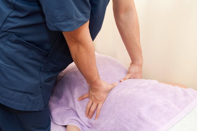 ぎっくり腰の根本原因である腰椎・仙腸関節・股関節の歪みと筋肉の癒着を、辛悦式推拿で剥離し正骨法でミリ単位の正確な位置へ調整している施術イメージ