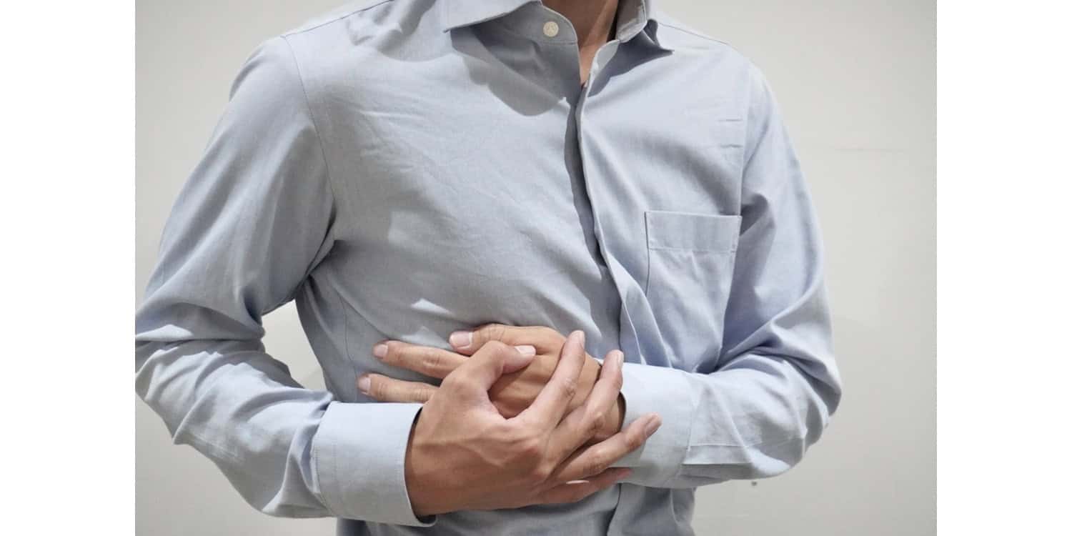 肋間神経痛で脇腹を痛そうに押さえている男性のイメージ画像