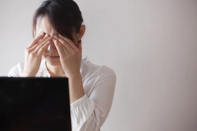 眼精疲労で目を押さえている女性のイメージ画像